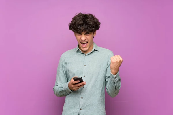 Joven Sobre Aislada Pared Púrpura Con Teléfono Posición Victoria —  Fotos de Stock