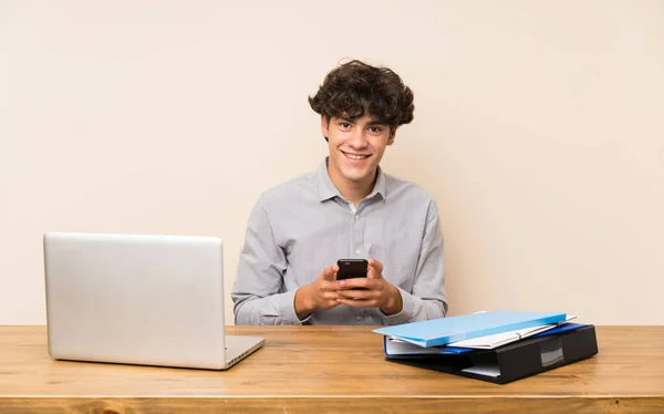 Jovem Estudante Com Laptop Enviando Uma Mensagem Com Celular — Fotografia de Stock