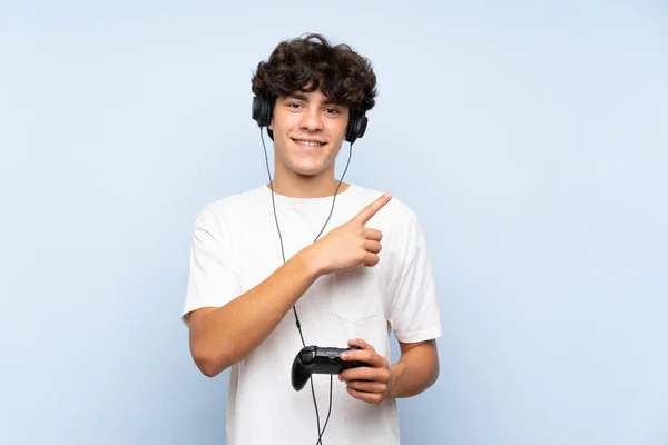 Νεαρός Άνδρας Παίζει Ένα Χειριστήριο Βιντεοπαιχνιδιών Πάνω Από Απομονωμένο Μπλε — Φωτογραφία Αρχείου
