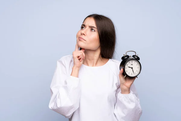 Jonge Vrouw Geïsoleerde Blauwe Achtergrond Met Vintage Wekker — Stockfoto