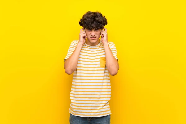 Zole Edilmiş Sarı Duvarlı Genç Adam Hayal Kırıklığına Uğramış Kulaklarını — Stok fotoğraf