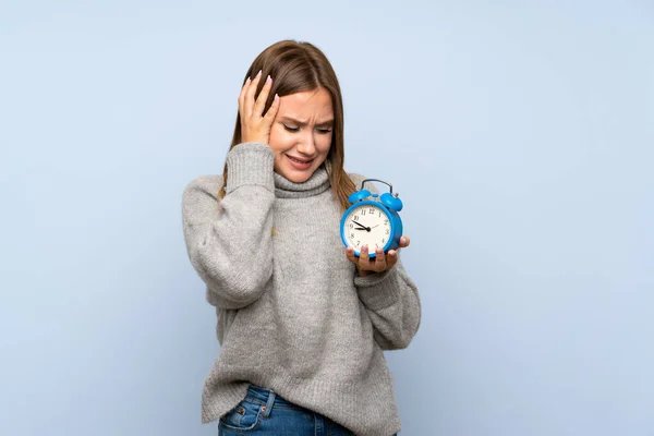 ヴィンテージ目覚まし時計を保持する孤立した青い背景の上にセーターを持つティーンエイジャーの女の子 — ストック写真