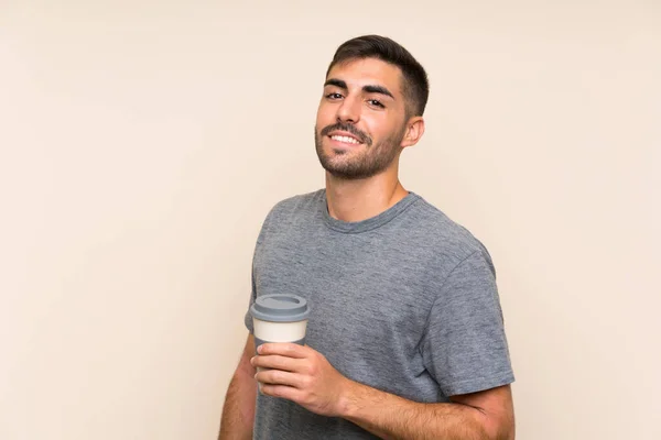 Beau homme avec barbe tenant un café à emporter sur fond isolé — Photo