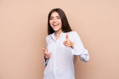 İzole edilmiş arka planda genç bir kadın ön tarafı gösteriyor ve gülümsüyor.