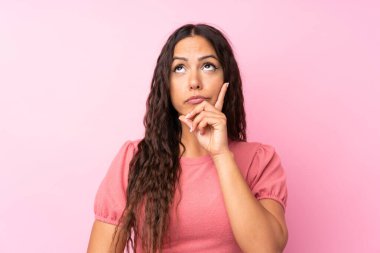 Soyutlanmış pembe arka planı olan genç bir kadın bir fikir düşünüyor.