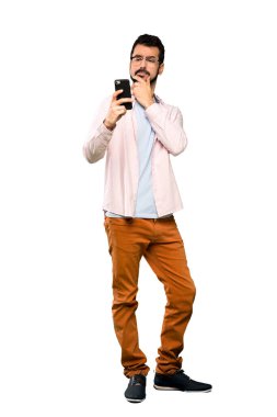 Sakallı, yakışıklı bir adamın izole edilmiş beyaz arka planda düşünüp mesaj gönderdiği uzun bir çekim.