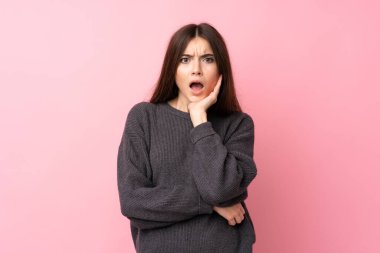 Soyutlanmış pembe arka planı olan genç bir kadın sağa bakarken şaşırmış ve şok olmuştu.