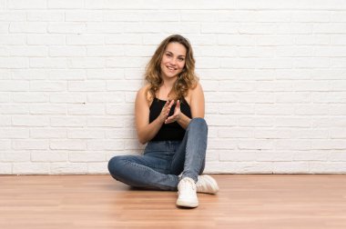 Genç sarışın kadın alkışlayarak katta oturan