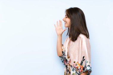 İzole edilmiş mavi arka planı olan beyaz bir kız ağzı açık bağırıyor.