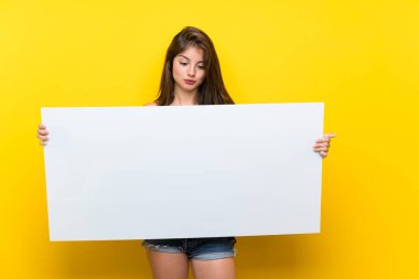 Izole sarı arka plan üzerinde renkli elbiseli Kafkas kız bir kavram eklemek için boş bir beyaz pankart tutarak