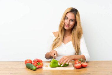 Bir masada sebze ile genç sarışın kadın