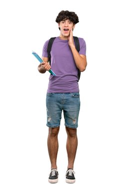 İzole edilmiş beyaz arka plan üzerinde şaşırmış ve şok olmuş bir yüz ifadesi olan genç bir öğrencinin tam boy fotoğrafı.