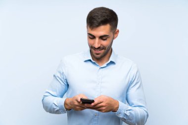 Izole mavi duvar üzerinde cep ile genç yakışıklı adam