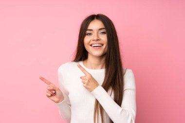 Soyutlanmış pembe arka planda genç bir kadın parmak gösteriyordu.