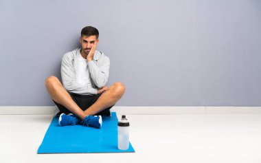 Spor adamı yerde oturuyor, mutsuz ve sinirli.