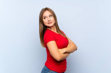 İzole edilmiş mavi arka planı olan genç kız gülüyor.