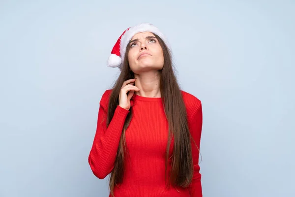 Meisje Met Kerst Hoed Geïsoleerde Blauwe Achtergrond Denken Een Idee — Stockfoto