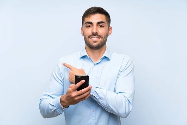 Ung Stilig Man Med Sin Mobil Över Isolerad Blå Vägg — Stockfoto