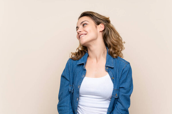 Young blonde woman over isolated background looking to the side