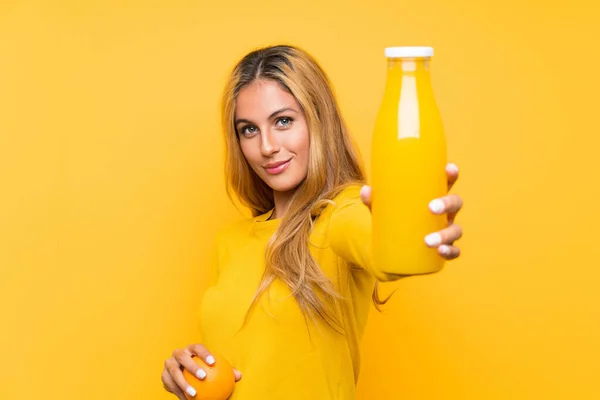 Junge Blonde Frau Hält Eine Orange Über Gelbem Hintergrund — Stockfoto
