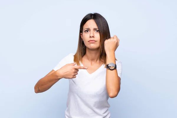 Jonge Vrouw Geïsoleerde Blauwe Achtergrond Tonen Hand Horloge Met Ernstige — Stockfoto