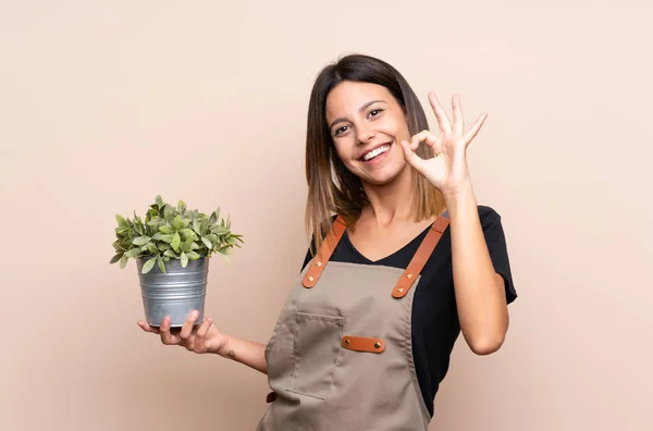 Jonge Vrouw Met Een Plant Tonen Teken Met Vingers — Stockfoto