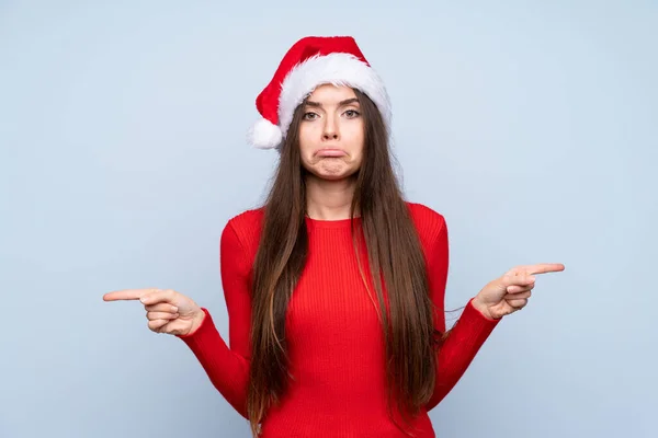 Girl Christmas Hat Isolated Blue Background Pointing Laterals Having Doubts — ストック写真
