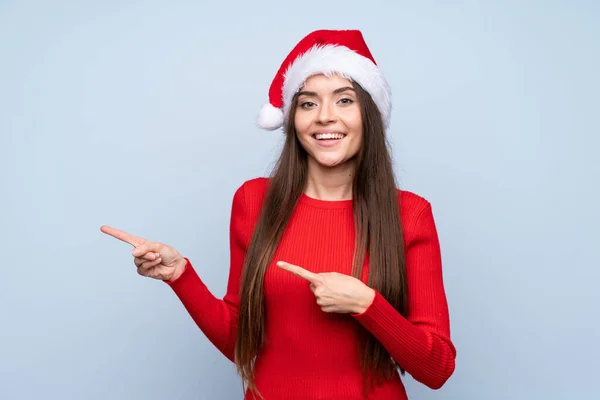 Menina Com Chapéu Natal Sobre Fundo Azul Isolado Apontando Dedo — Fotografia de Stock