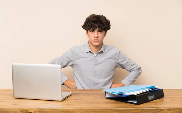 Young student man with a laptop angry