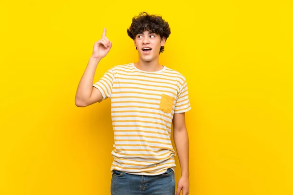 Sarı Duvarı Aşan Genç Adam Parmağını Kaldırarak Çözümü Bulmaya Çalışıyor — Stok fotoğraf