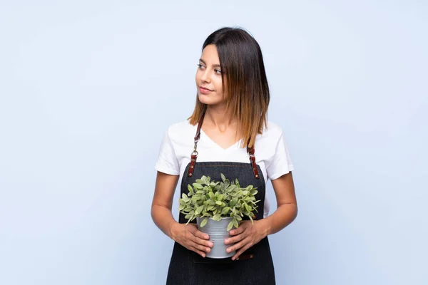 Jonge Vrouw Geïsoleerde Blauwe Achtergrond Het Nemen Van Een Bloempot — Stockfoto