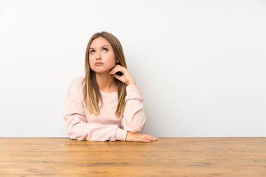 Masadaki genç kız bir fikir düşünüyor.