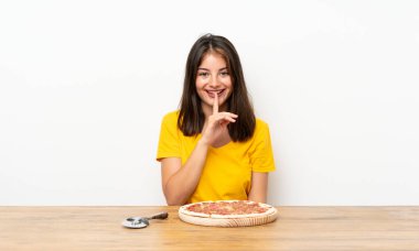 Elinde pizza olan beyaz bir kız sessizlik hareketi yapıyor.