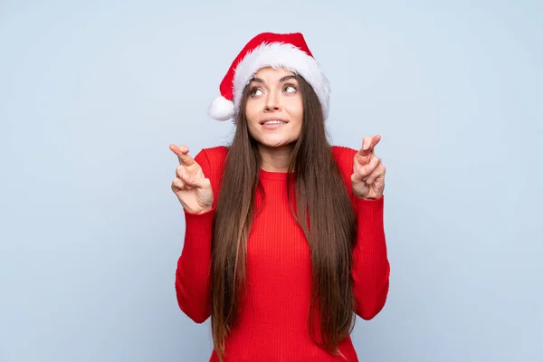 女の子とともにクリスマス帽子以上隔離された青の背景とともに指交差 — ストック写真