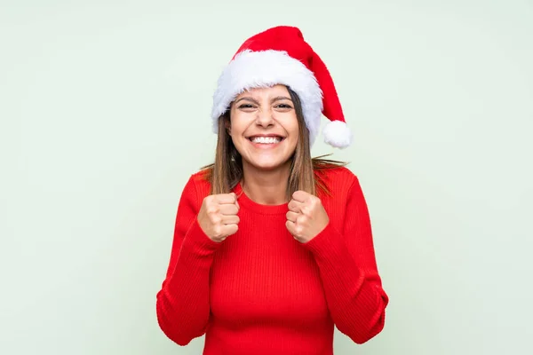 Zole Edilmiş Yeşil Arka Planda Noel Şapkalı Kız Zaferi Kutluyor — Stok fotoğraf