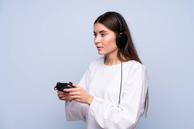 İzole edilmiş mavi arka plan video oyunlarında oynayan genç bir kadın.