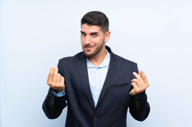 Soyutlanmış mavi arka planda yakışıklı bir adam para hareketi yapıyor.