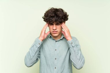 İzole edilmiş yeşil duvarın üzerindeki genç adam mutsuz ve bir şeyden hayal kırıklığına uğramış. Olumsuz yüz ifadesi