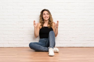 Genç sarışın kadın yerde oturuyor ve dua ediyor.