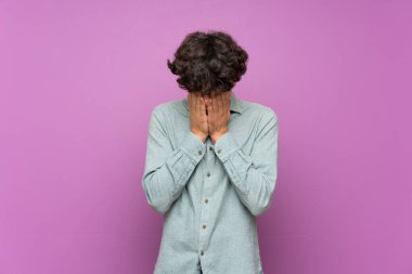 Yorgun ve hasta ifade ile izole mor duvar üzerinde genç adam