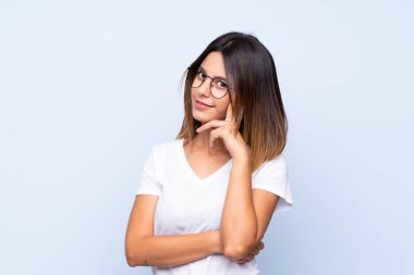 Gözlüklü, soyutlanmış mavi arka planı olan genç bir kadın.