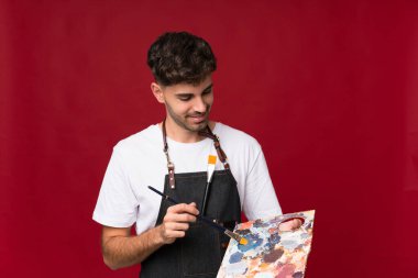 Soyutlanmış arka planda palet tutan genç bir adam.