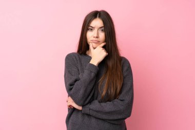 Soyutlanmış pembe arka plan düşünen genç bir kadın.