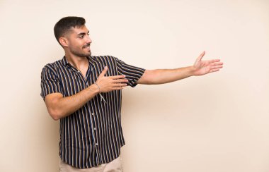 Izole arka plan üzerinde sakallı yakışıklı adam gelmeye davet için yan ellerini uzatarak