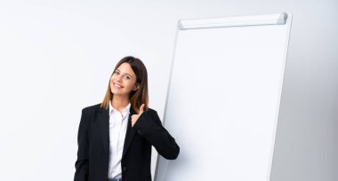 Beyaz panoda sunum yapan genç bir kadın. Başparmakları havada. Çünkü iyi bir şey oldu.