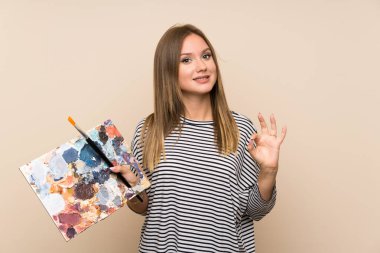 Genç kız parmakları ile ok işareti gösteren izole arka plan üzerinde bir palet tutan