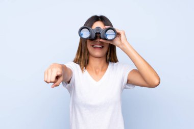 Siyah dürbünle izole edilmiş mavi arka planı olan genç bir kadın.