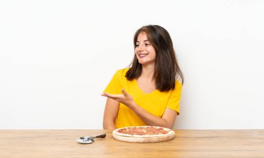 Beyaz kız pizza ile gelen davet için yan ellerini uzatıyor