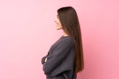 Yanal pozisyonda pembe arka plan üzerinde genç bir kadın.