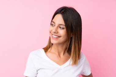 Soyutlanmış pembe arka planı olan genç bir kadın